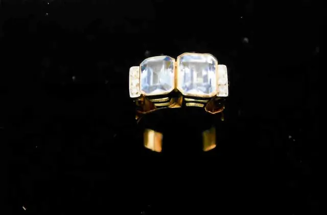 Um ANEL, pesando 9,5 gramas, em ouro 18 k, com seis BRILHANTES, com duas águas marinhas sintéticas