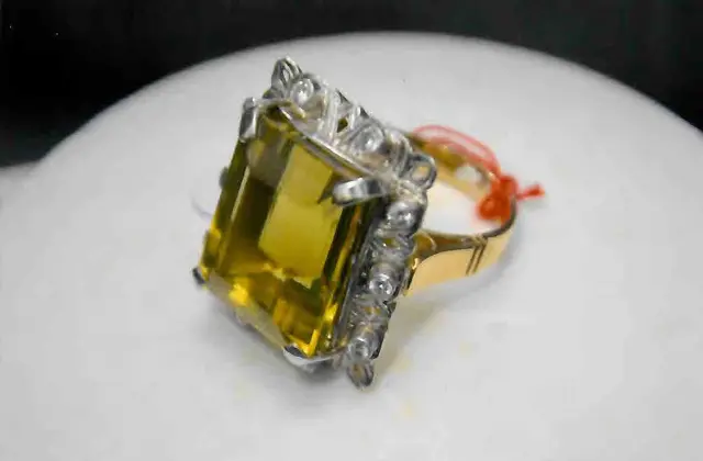 Um ANEL, pesando de 21,3 gramas, em OURO 18 k e PLATINA, dez BRILHANTES e um TOPÁZIO