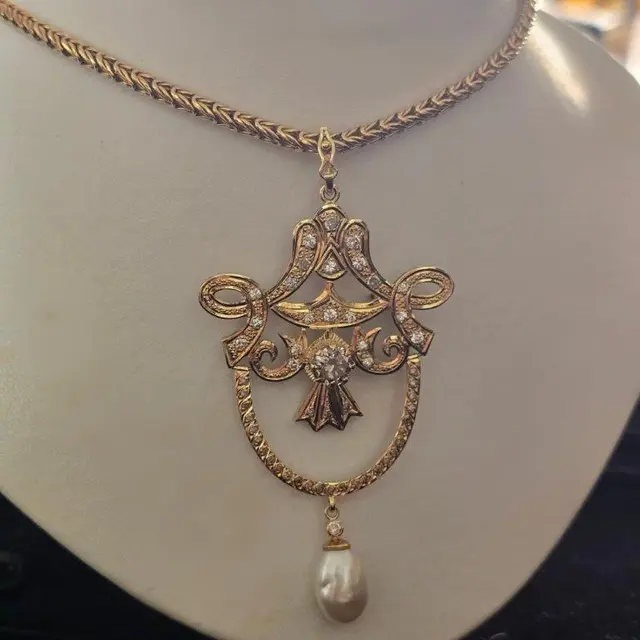 Um COLAR, pesando 38,4 gramas, em ouro 18 k, com BRILHANTE de 1,50 k, cinquenta BRILHANTES e uma PÉROLA